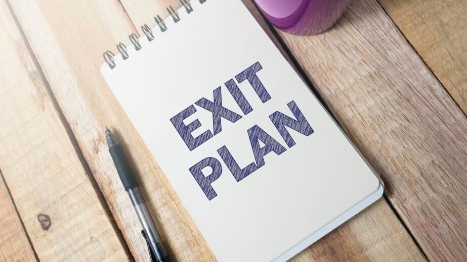Notebook page reading "Exit Plan" with a pen, representing exit strategy planning for business owners